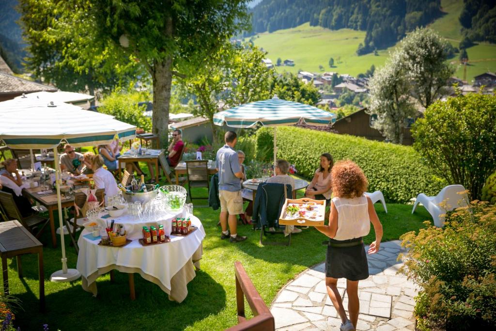 a group of people sitting at tables in a garden at Hotel & Spa Le Dahu in Morzine