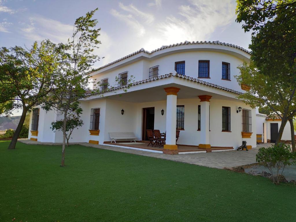 uma grande casa branca com um relvado em frente em Cortijo El Arrejadero em Villanueva del Rosario