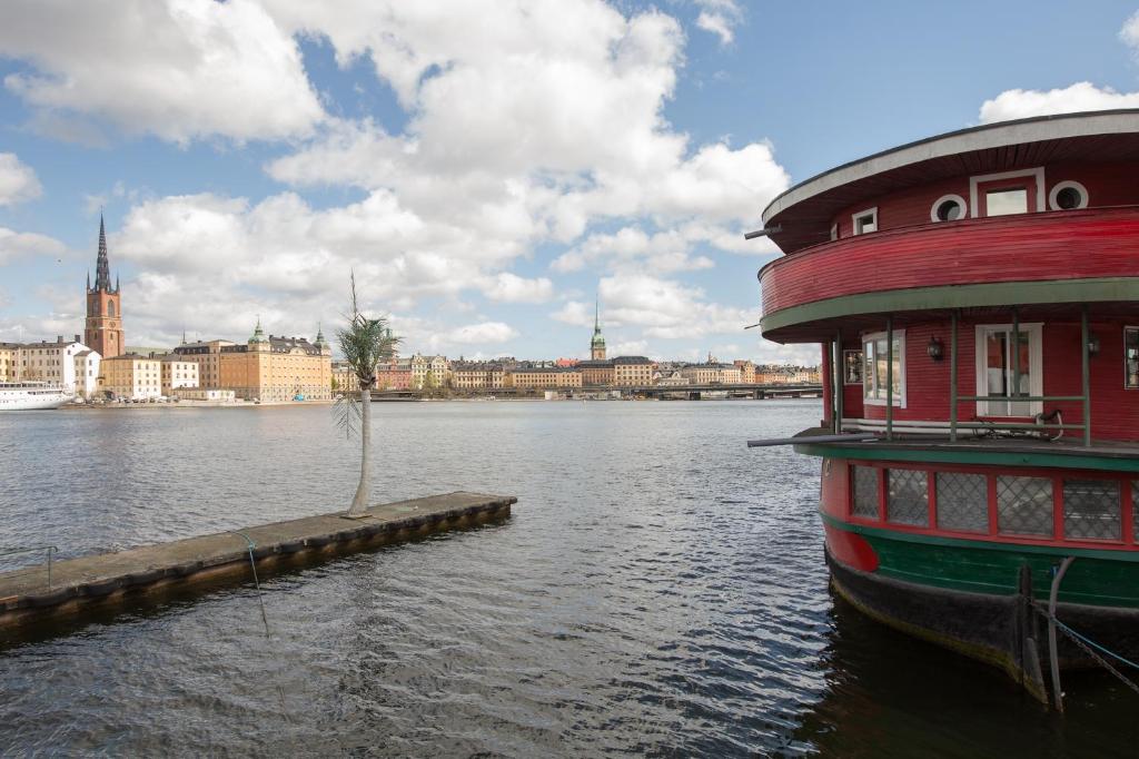 a boat on the water with a city in the background at Den Röda Båten in Stockholm