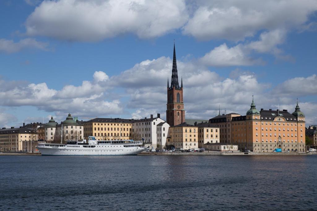 a cruise ship in the water in front of a city at Den Röda Båten in Stockholm