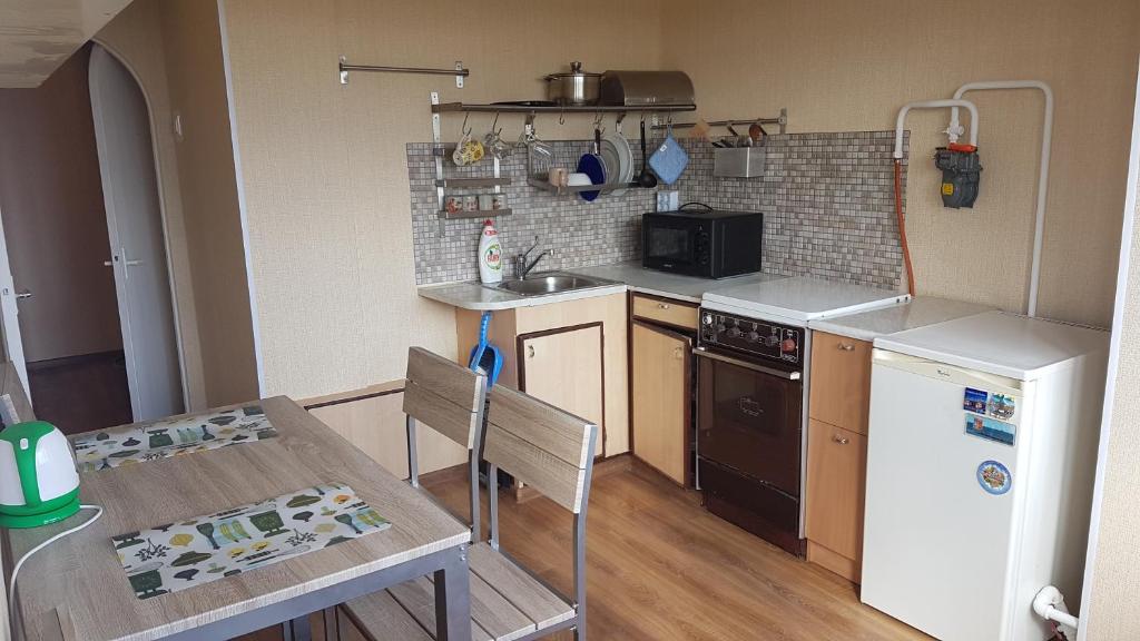 a small kitchen with a table and a refrigerator at Apartament Erfolg 1 in Daugavpils