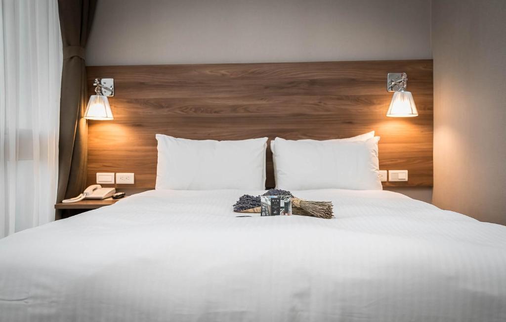 a bedroom with a white bed with a wooden headboard at Hotel Leisure Beitou in Taipei