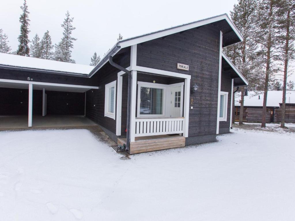 a black house with a white door in the snow at Holiday Home Pihkala 2 by Interhome in Äkäslompolo