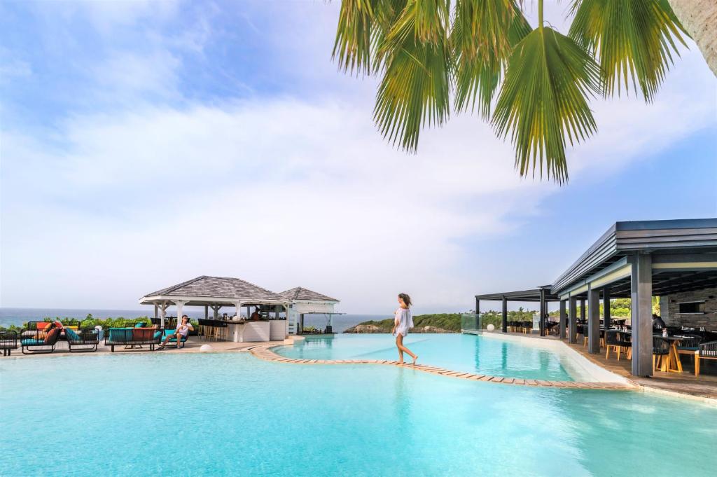 a woman walking on a rope around a pool at a resort at La Toubana Hotel & Spa in Sainte-Anne