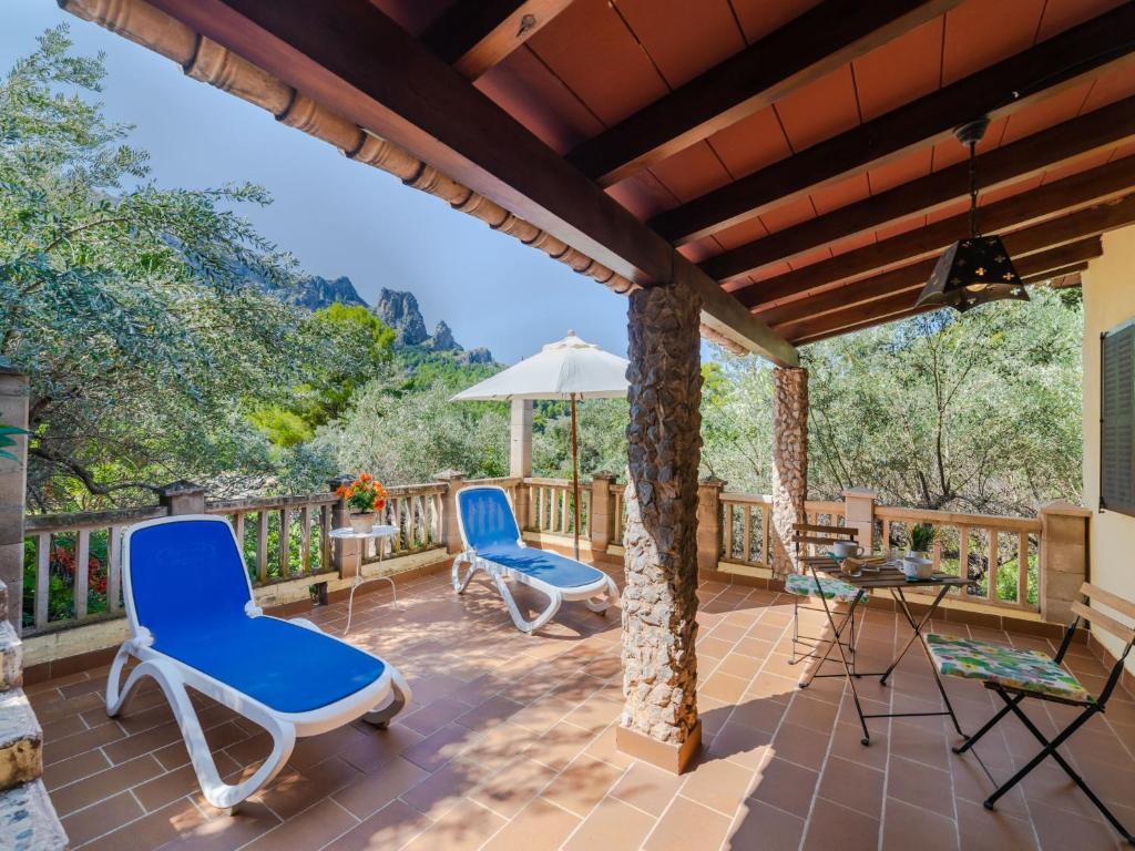 eine Terrasse mit Stühlen, einem Tisch und einem Sonnenschirm in der Unterkunft Holiday Home Cala Tuent by Interhome in Cala Tuent