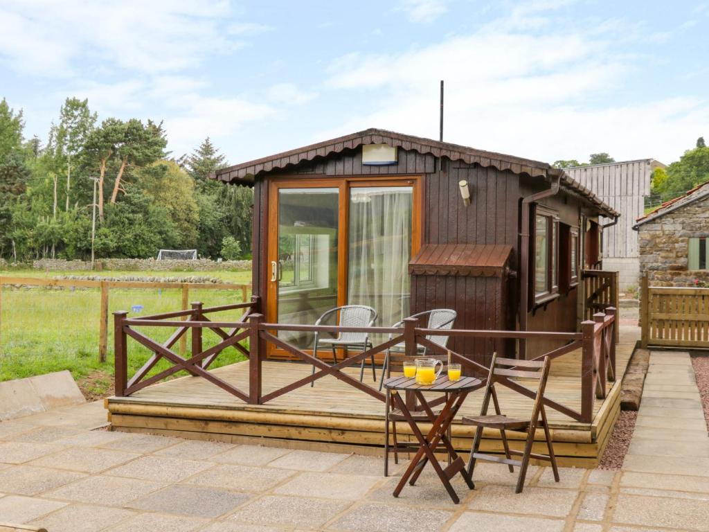 a tiny house with a deck and a table at Thirley Beck Lodge in Scarborough