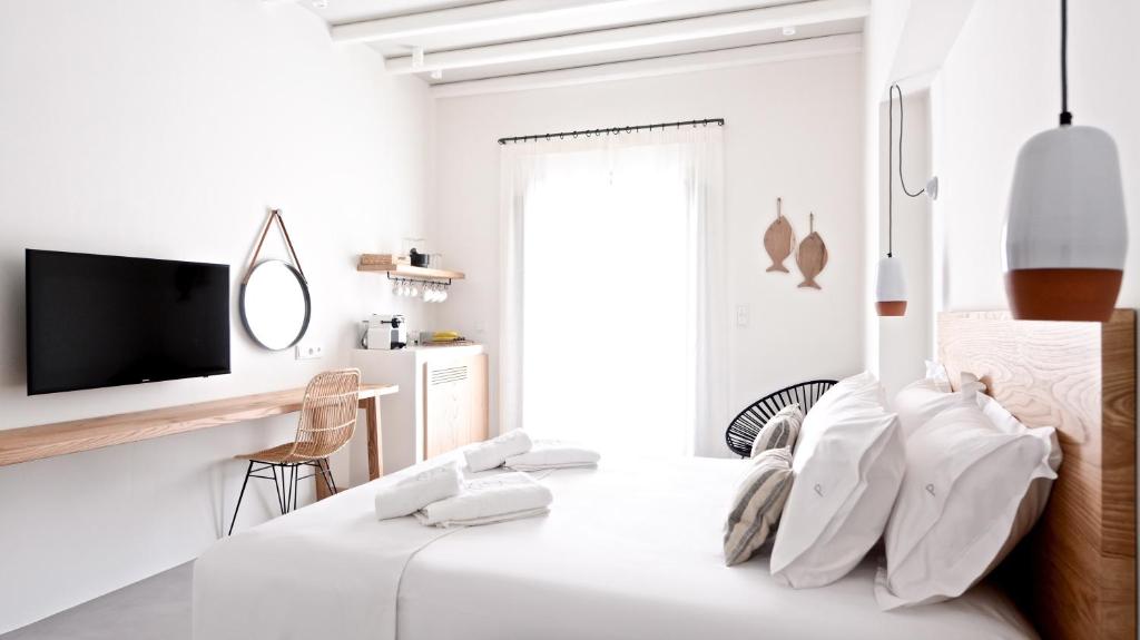 a white room with a bed and a tv at Pénde Suites in Livadion