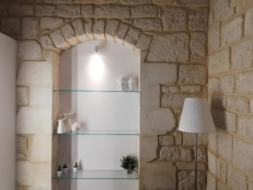 a room with a stone wall with glass shelves at Triskelion in Scicli