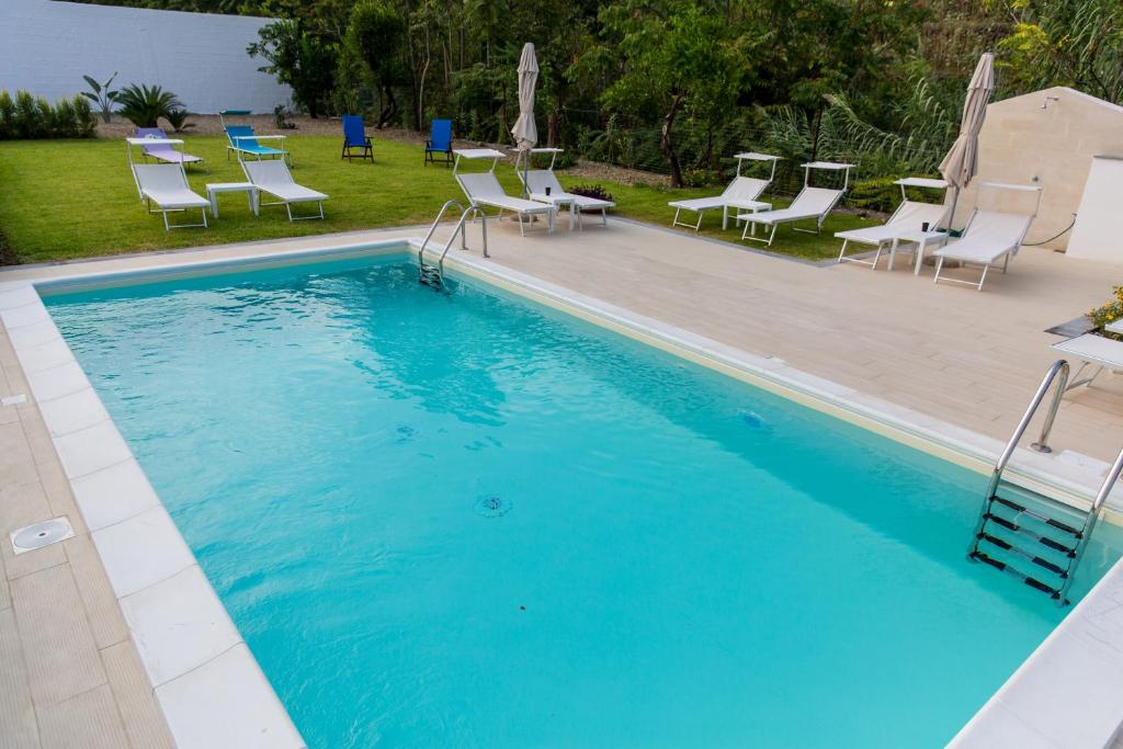a large blue swimming pool with chairs at Veda elegant rooms in Fiumefreddo di Sicilia