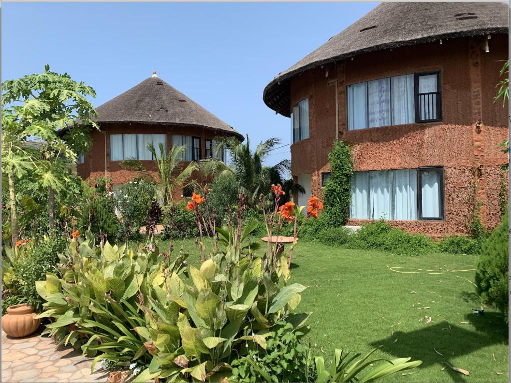 uma casa com um jardim de relva com flores à frente em Marcelo Beach Club em Lomé