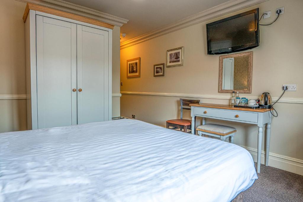 a bedroom with a bed and a desk and a television at Botany Bay Hotel in Broadstairs