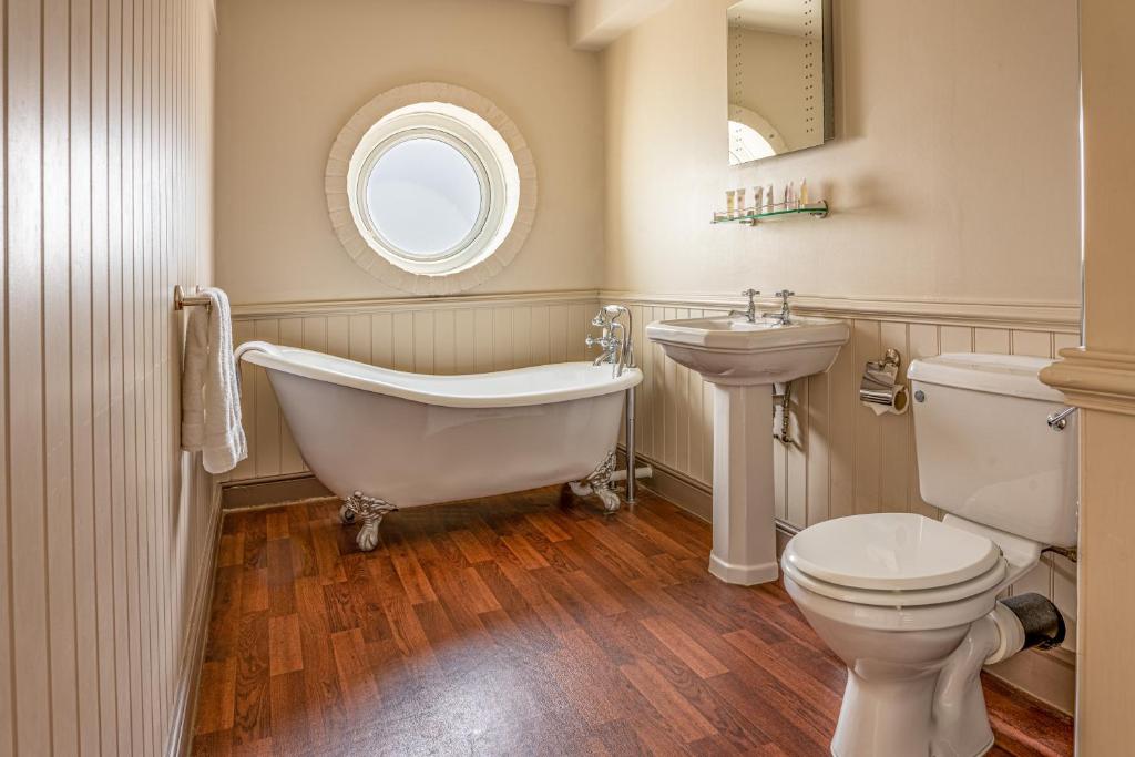 a bathroom with a tub and a toilet and a sink at Botany Bay Hotel in Broadstairs