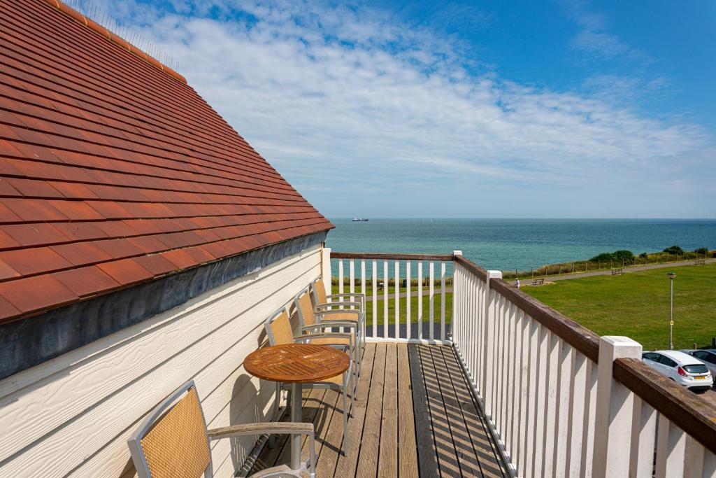 a balcony with chairs and a table and the ocean at Botany Bay Hotel in Broadstairs