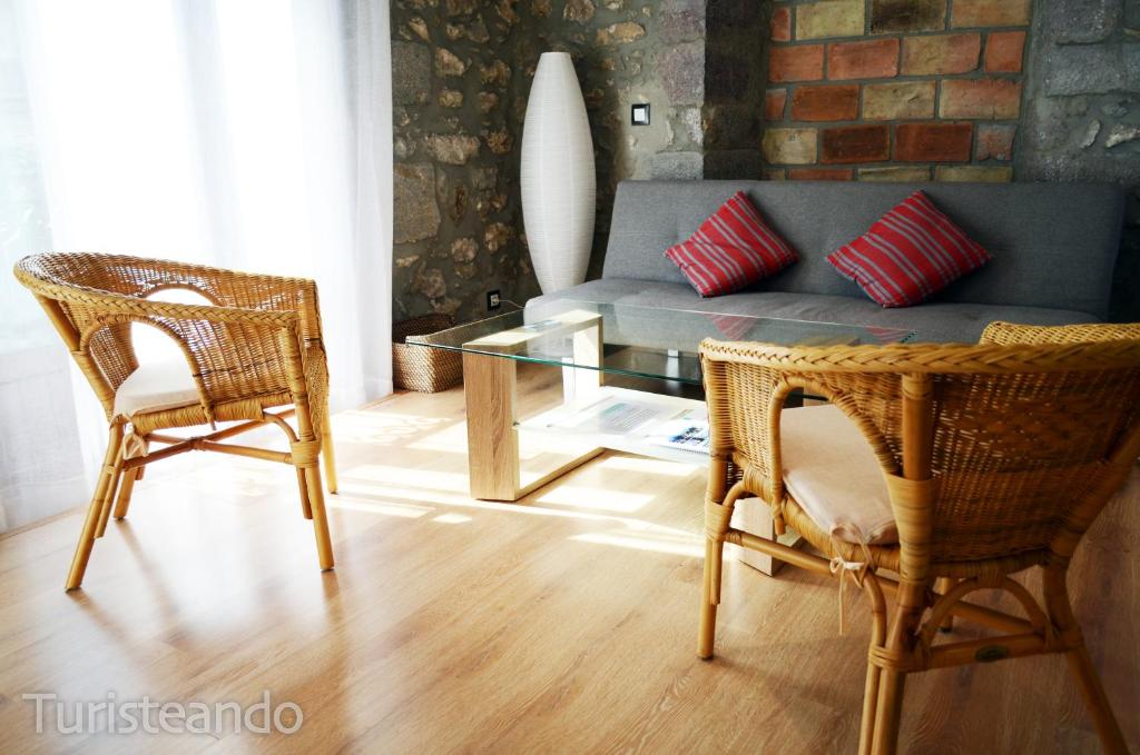 uma sala de estar com um sofá, 2 cadeiras e uma mesa de vidro em Apartamento Llerandi 1C - Ideal para dos personas em San Vicente de la Barquera