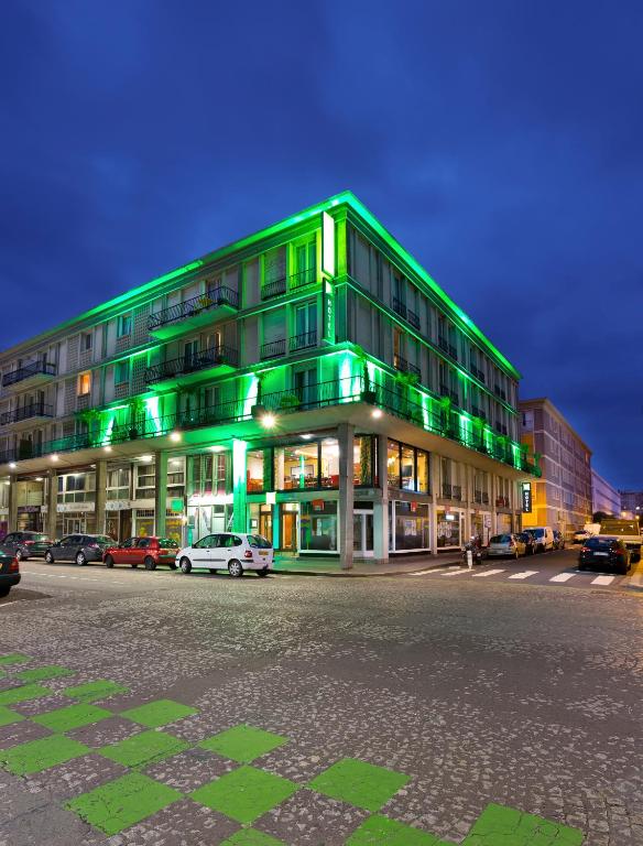 un bâtiment vert avec des voitures garées devant lui dans l'établissement ibis Styles Le Havre Centre, au Havre