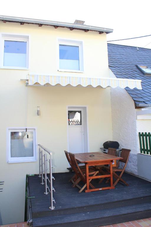 a patio with a wooden table and chairs in front of a house at Ferienhaus Milena in Lieser