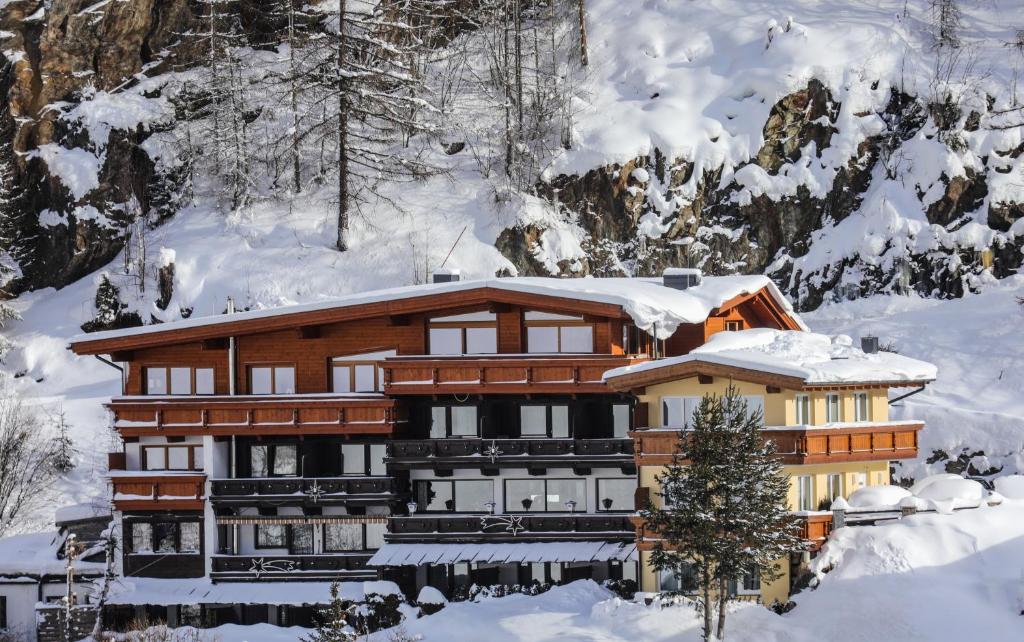 un edificio cubierto de nieve frente a una montaña en Pension Andreas, en Sölden