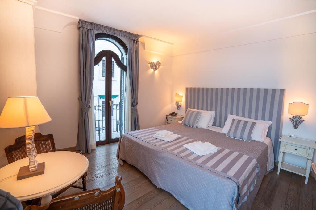 a bedroom with a bed and a table and a window at Covo dei Saraceni in Polignano a Mare