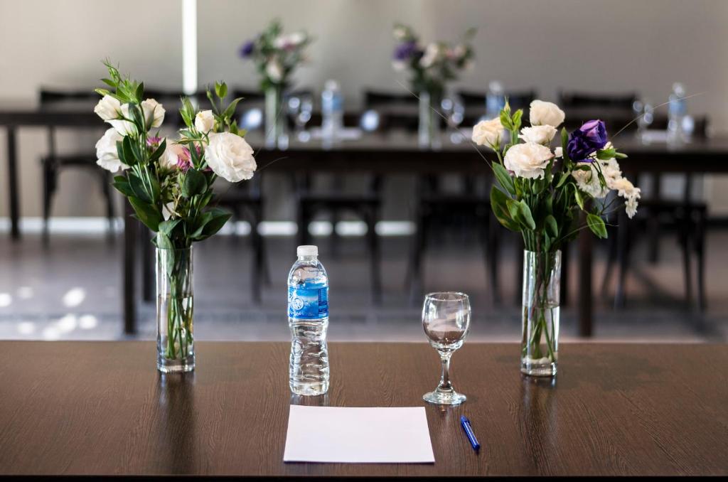 two vases with flowers and a bottle of water on a table at Villa Mansa in Vistalba