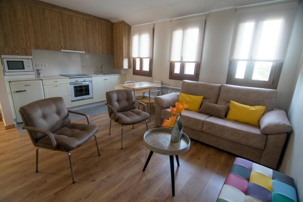 a living room with a couch and chairs and a table at Alojamientos MYL in Arzúa