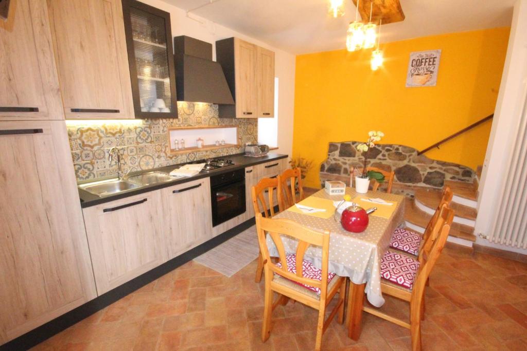 a kitchen with a table and chairs and a kitchen with yellow walls at L’ANGOLETTO in San Lorenzo Nuovo
