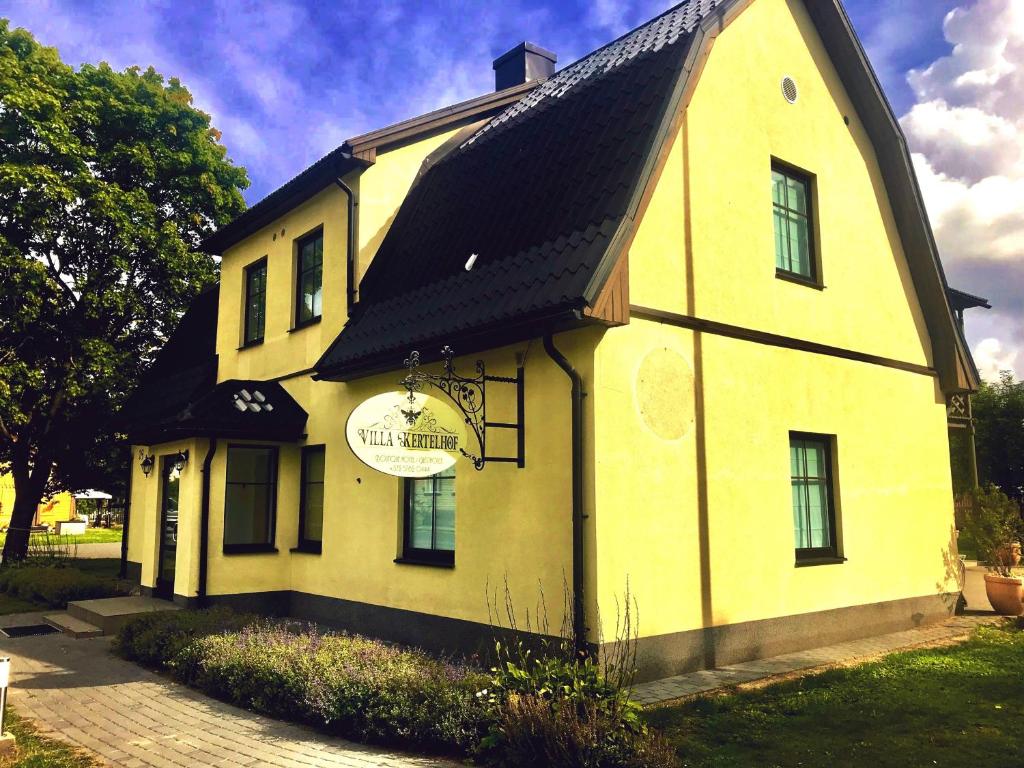 uma casa amarela com um telhado preto em Villa Kertelhof Guesthouse em Kärdla