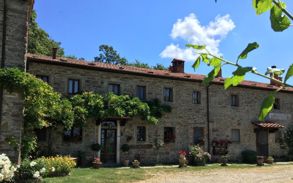 un vecchio edificio in pietra con dei fiori di fronte di Casina Della Burraia a Subbiano