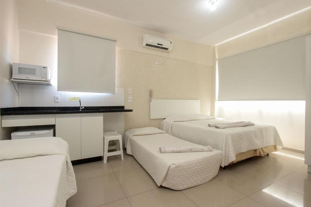 um quarto de hotel com duas camas e uma cozinha em Ilha Norte Apart Hotel em Florianópolis