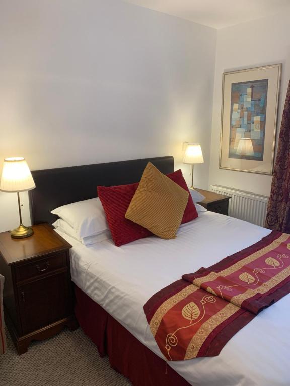 1 dormitorio con 1 cama grande con almohadas rojas y doradas en Jessamine House Hotel, en Gravesend