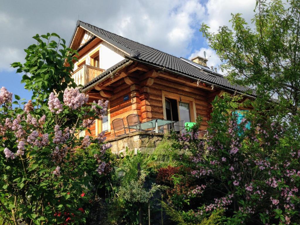 una cabaña de madera en el bosque con flores en Moja chata do wynajęcia en Istebna