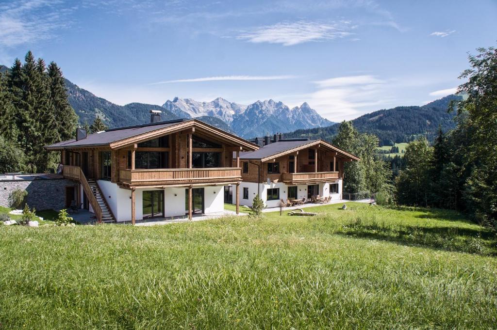 a house in a field with mountains in the background at Zeitfrei Chalet Apartments in Fieberbrunn