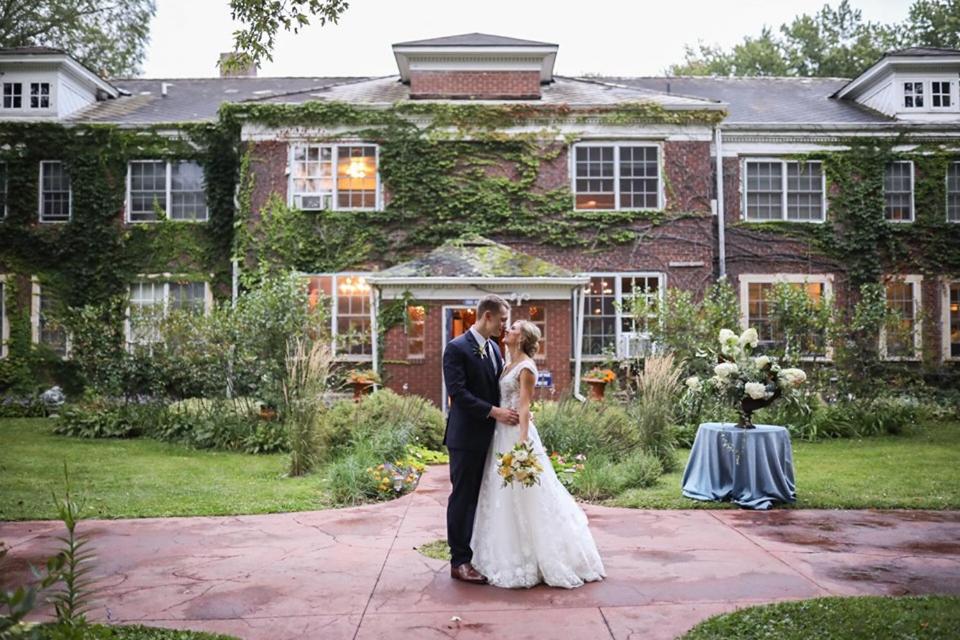 a bride and groom standing in front of a house at The Outing lodge in Stillwater