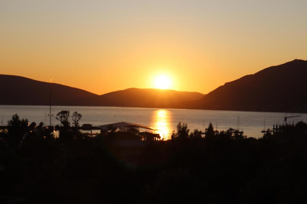 a sunset over the water with mountains in the background at Boka Bay in Tivat