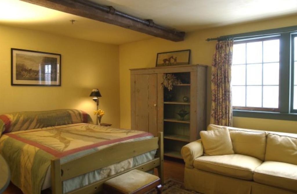 1 dormitorio con 1 cama y 1 sofá en Gedney Farm en New Marlborough