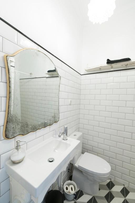 a white bathroom with a sink and a mirror at Bohemian Antique Guesthouse in Odeceixe