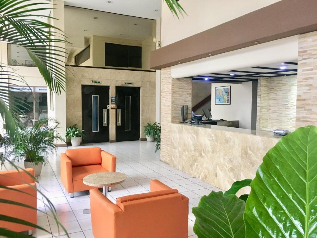 un vestíbulo de oficina con sillas naranjas y un mostrador en Hotel Ambassador, en San José