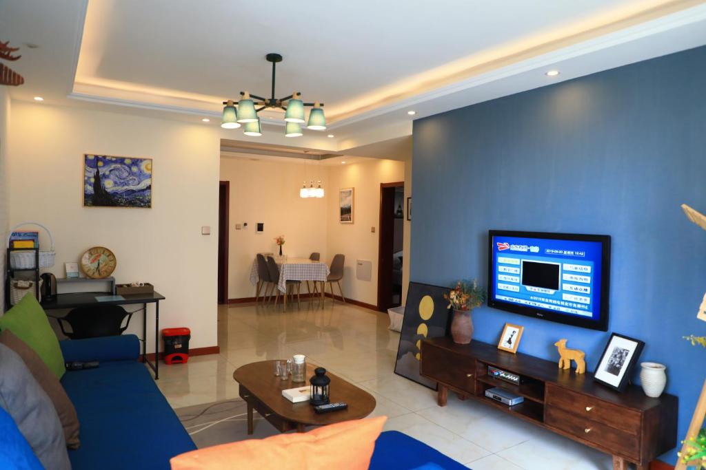 a living room with a blue wall with a tv at Sea View Apartment Qingdao North Railway Station Branch in Xiazangtuan