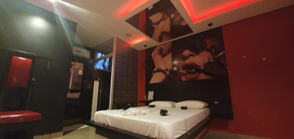ein Schlafzimmer mit einem weißen Bett mit einem Poster von Mädchen in der Unterkunft Ápice Motel in Jaguariúna