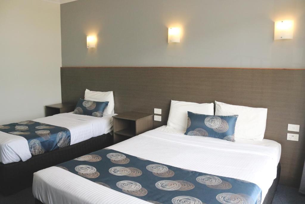 Habitación de hotel con 2 camas y almohadas azules y blancas en The Sands Motel Adelaide en Adelaida