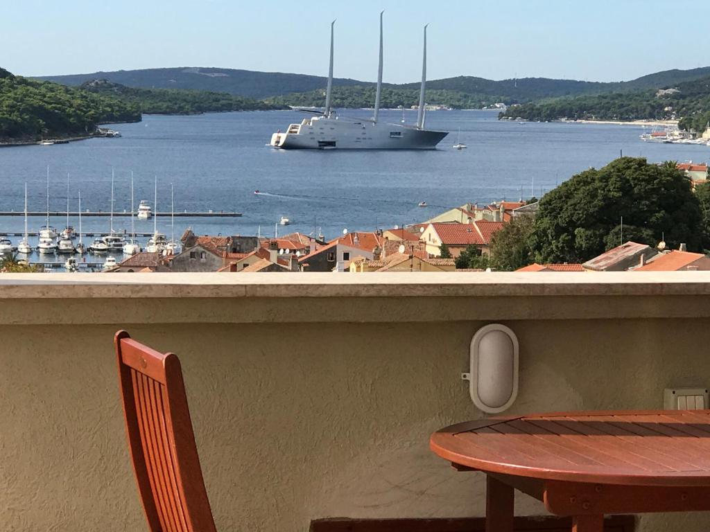 a balcony with a table and a boat in the water at Losinj Panorama Penthouse in Mali Lošinj