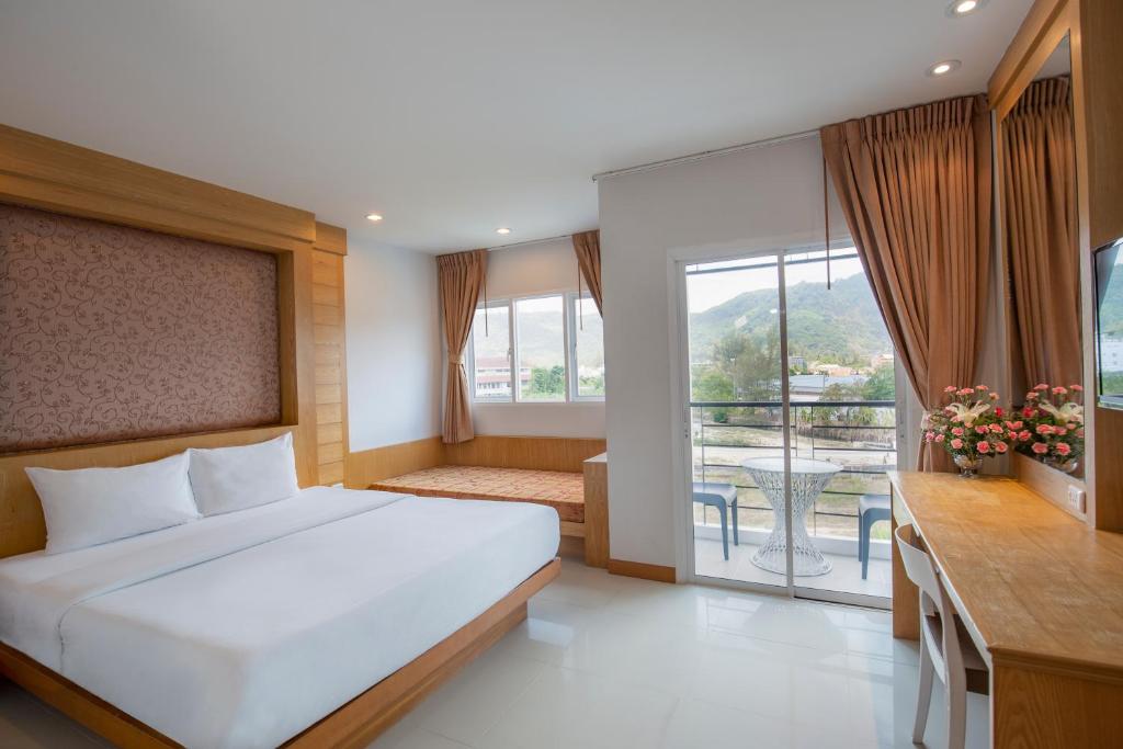 a bedroom with a large bed and a balcony at Sungthong Kamala Beach Resort in Kamala Beach