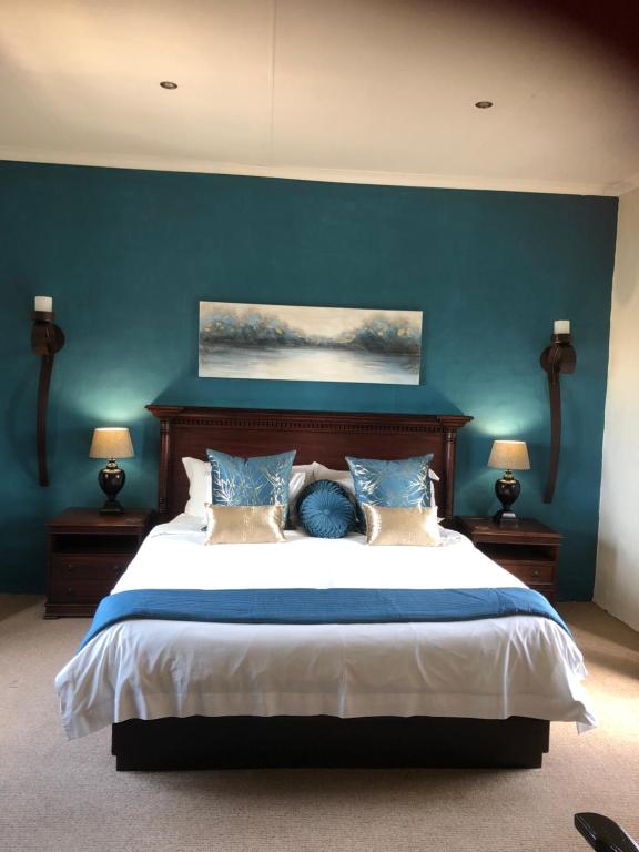 a bedroom with a bed, a desk, and a lamp at Dio Dell Amore Guest House in Jeffreys Bay