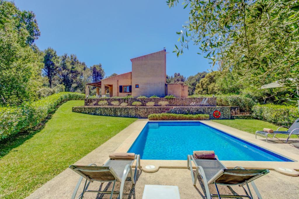 een zwembad met twee stoelen en een huis bij Villa Comella in Artá