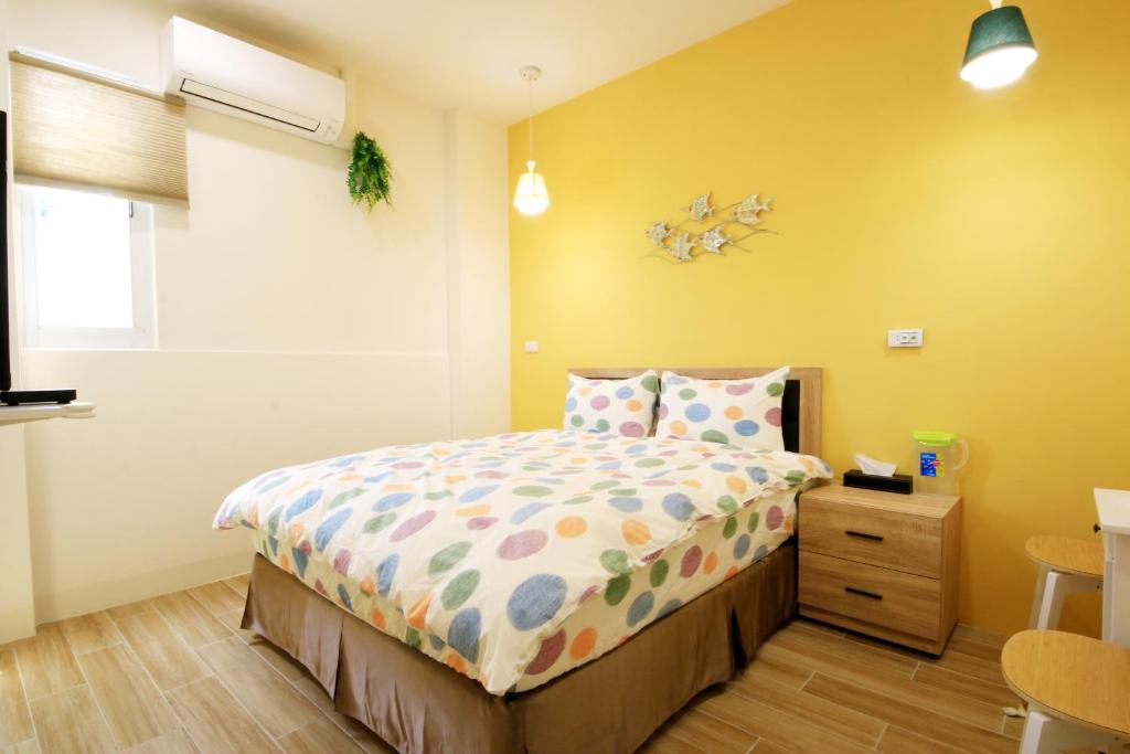 1 dormitorio con cama y pared amarilla en The Wind BnB Ⅱ, en Budai