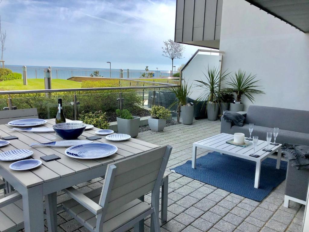 einen Tisch mit Tellern und eine Flasche Wein auf einer Terrasse in der Unterkunft Sea Breeze in Bournemouth