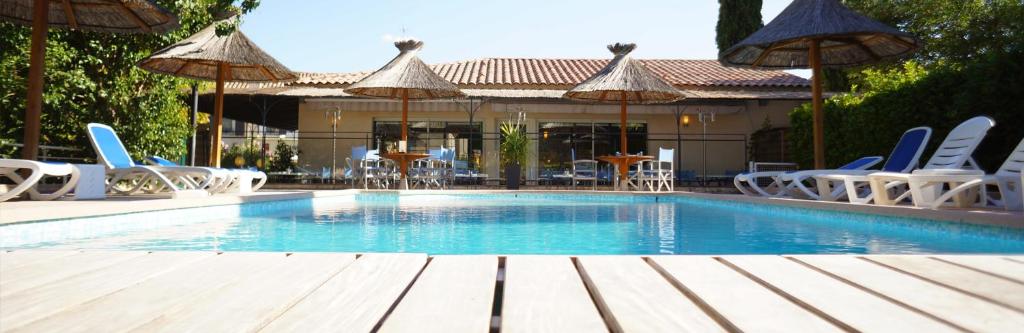 een zwembad met stoelen, tafels en parasols bij Hôtel des Alpes in Gréoux-les-Bains