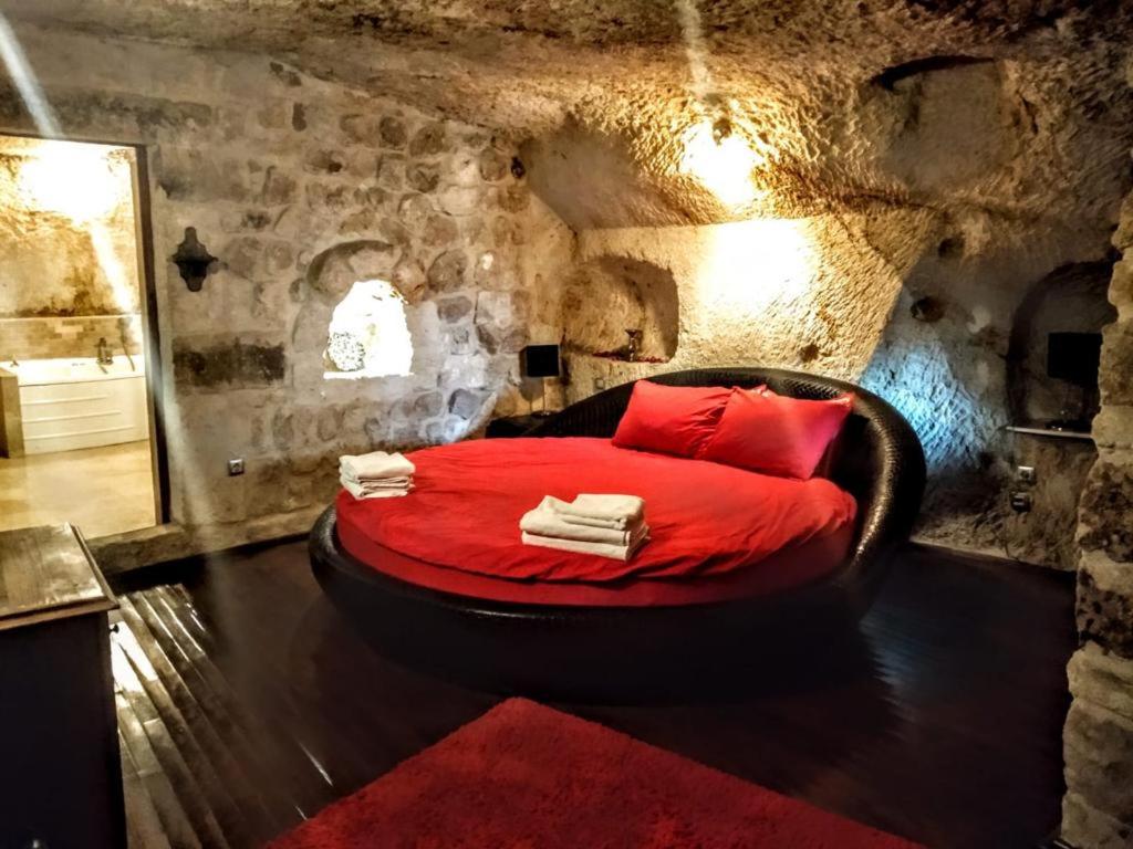 a bedroom with a red bed in a stone room at ROCA CAPPADOCIA in Urgup