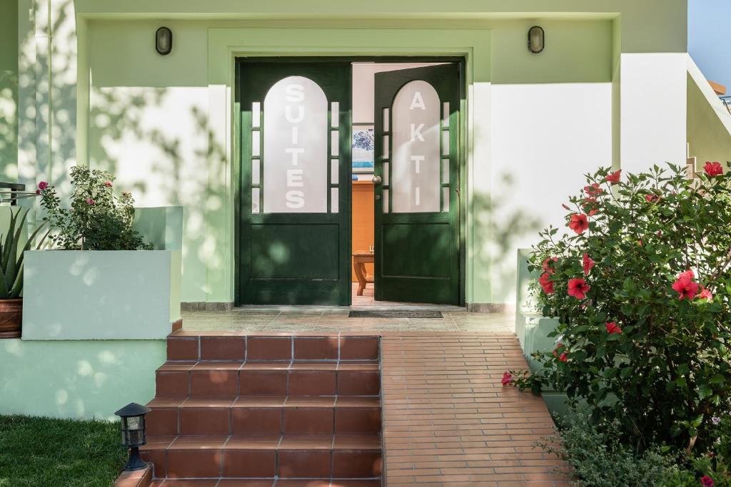 Akti Suites في كاتو داراتسو: باب أخضر على منزل به زهور حمراء
