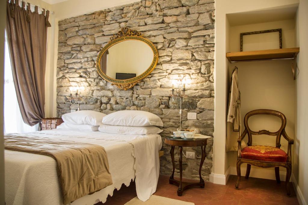 ein Schlafzimmer mit einer Steinmauer, einem Bett und einem Spiegel in der Unterkunft Residence Briona in Domodossola