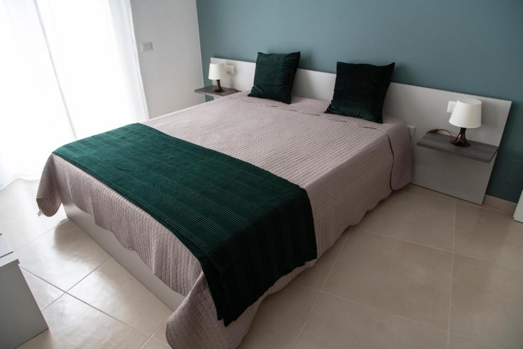a bedroom with a large bed with a green blanket at CASA VITTORIA in Gravina in Puglia